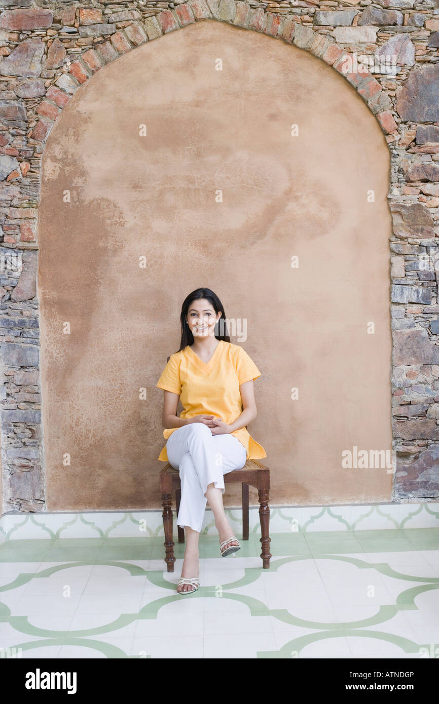 Portrait of a young woman sitting on a chair and smiling Stock Photo ...