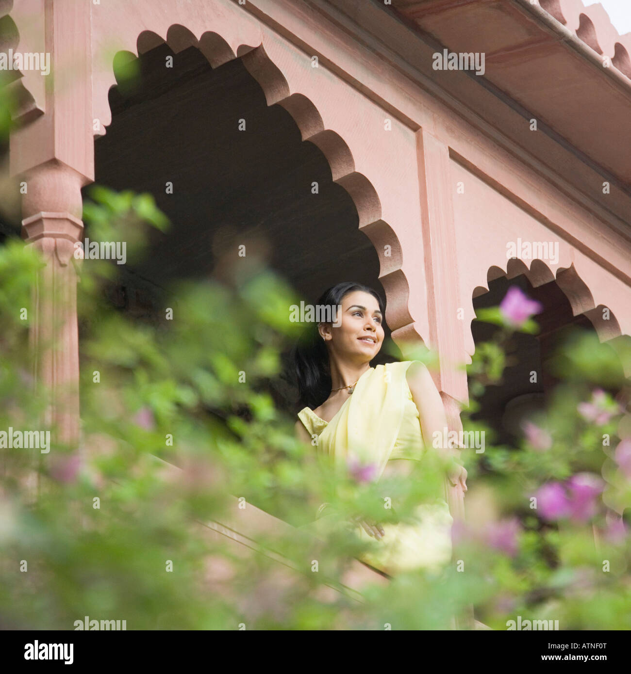 Young woman sitting on the railing of a palace, Neemrana Fort Palace, Neemrana, Alwar, Rajasthan, India Stock Photo
