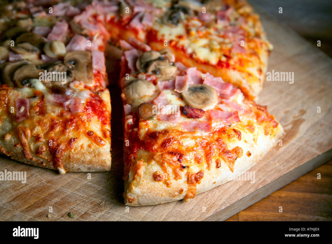 a-large-cheese-ham-and-mushroom-pizza-with-a-slice-ready-to-be-eat