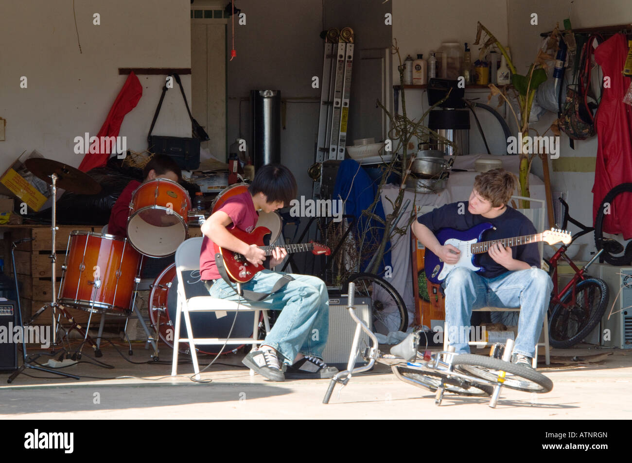 Three teenage boys who have formed a garage band, practice music in a