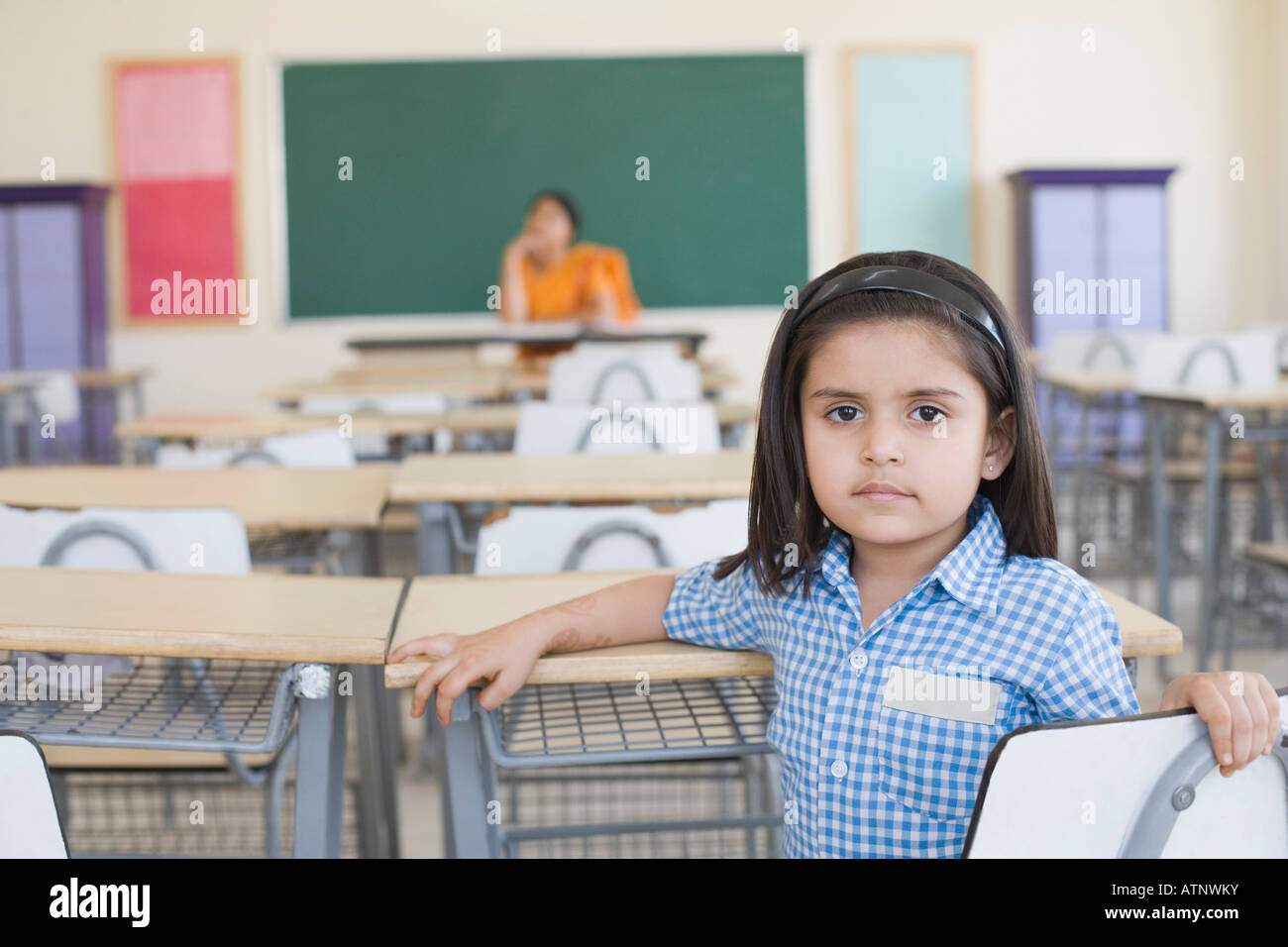 Portrait of a schoolgirl with her teacher sitting in the background ...