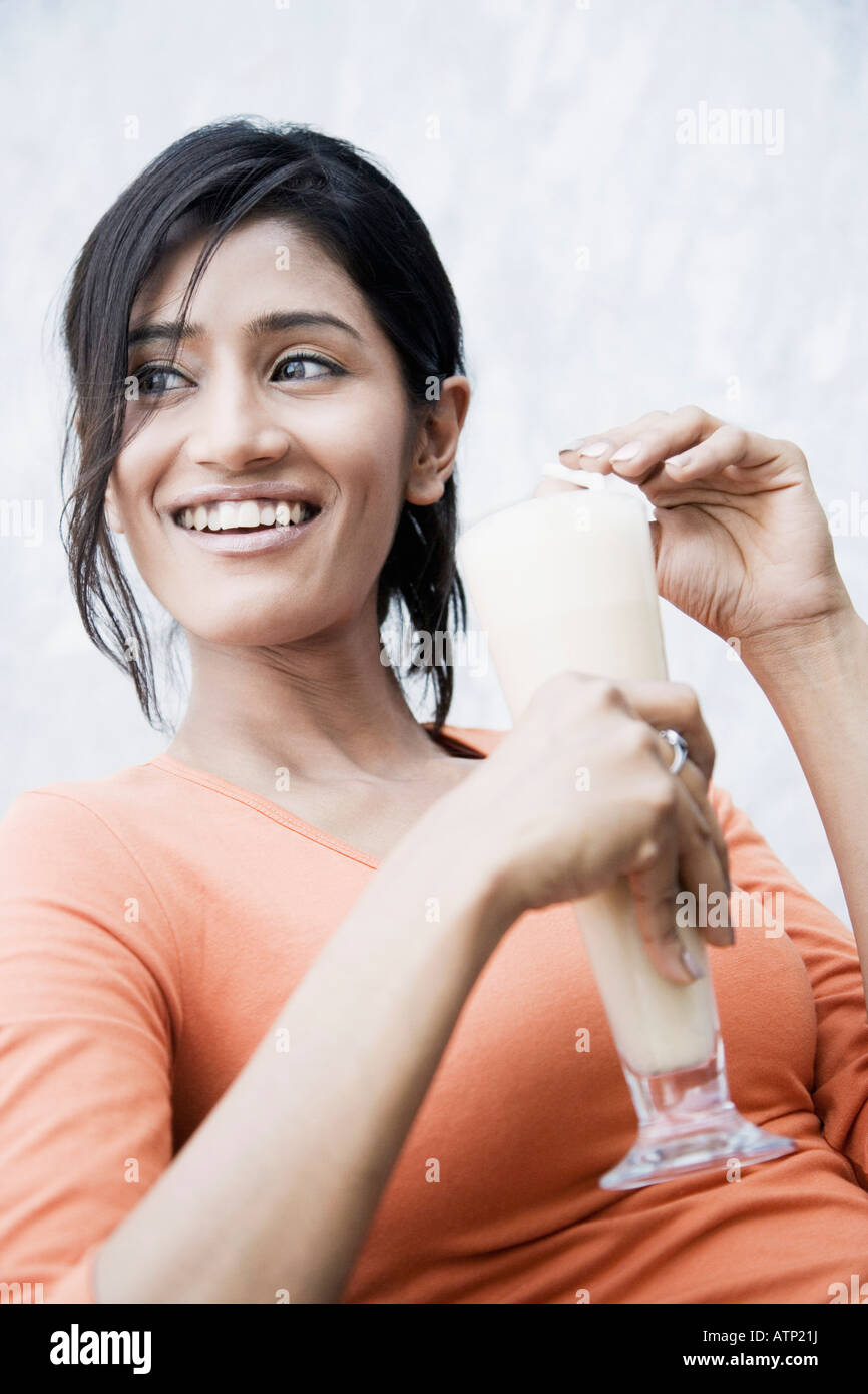 Close-up of a young woman holding a glass of milkshake and smiling Stock Photo