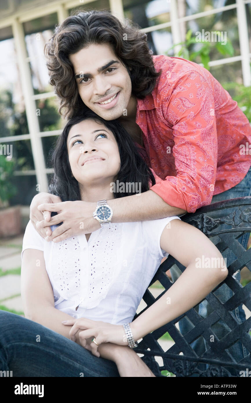 Portrait of a young man embracing a young woman from behind Stock Photo ...