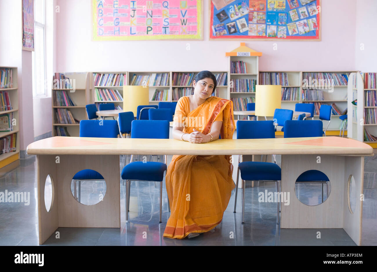 Female teacher sitting at a desk in a library Stock Photo