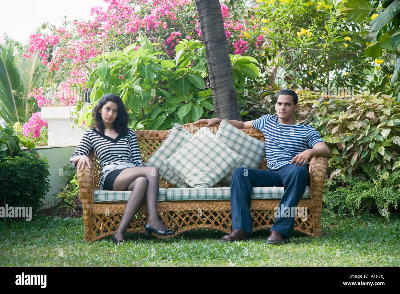 Young couple sitting on a couch in a park Stock Photo - Alamy