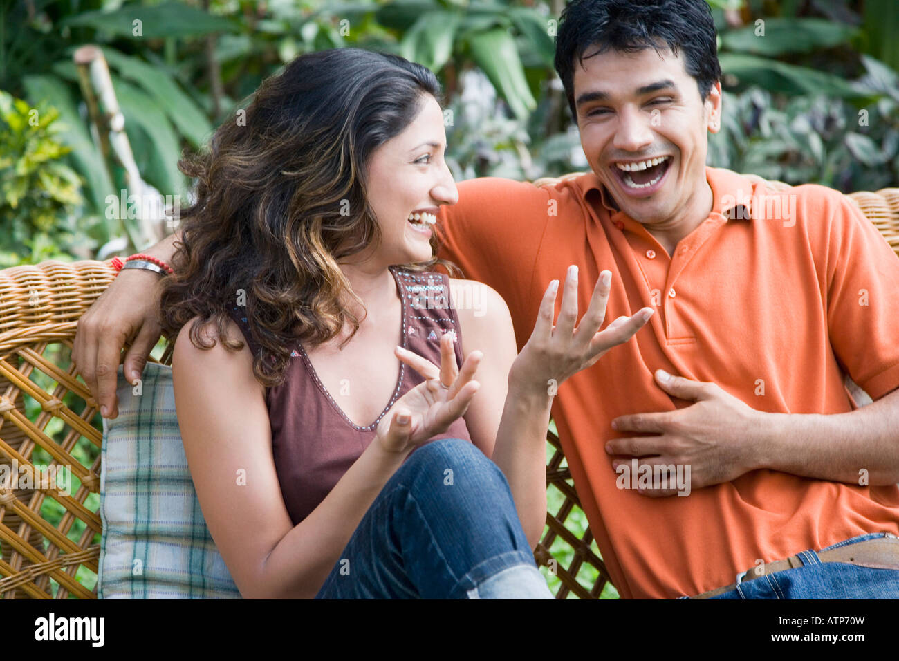 Young couple sitting on a couch and smiling Stock Photo - Alamy