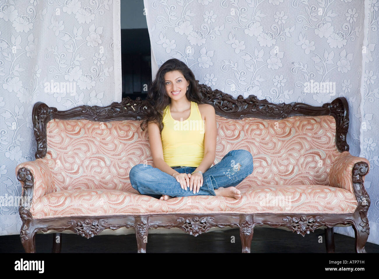 Portrait of a young woman sitting on a couch and smiling Stock Photo ...