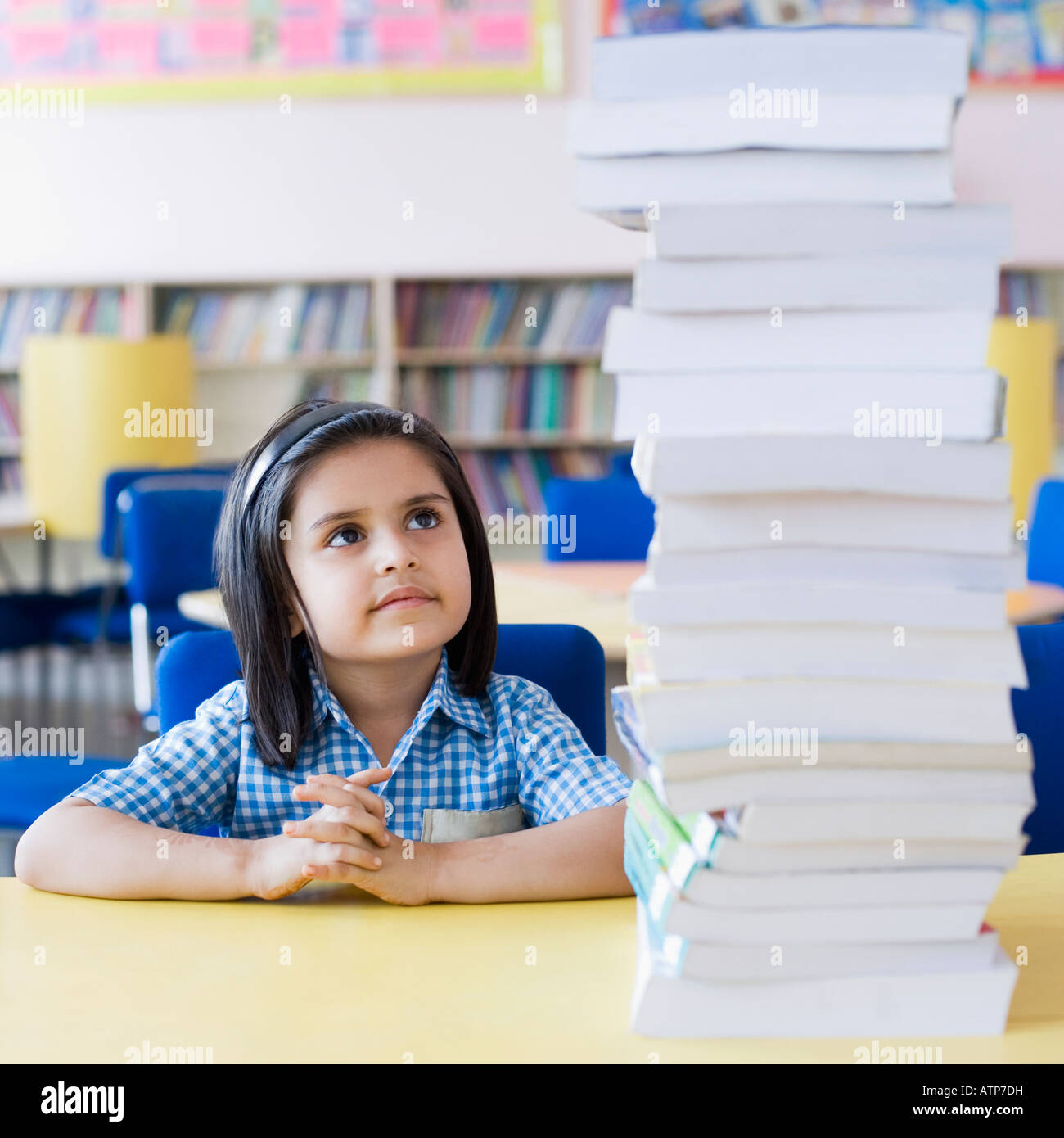 Schoolgirl looking at a stack of books Stock Photo - Alamy