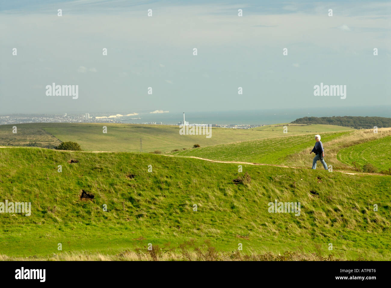 A woman walking at Cissbury Ring Findon near Worthing Hazey day View of seven Sisters Brighton and Hove and Shoreham Sea in dist Stock Photo