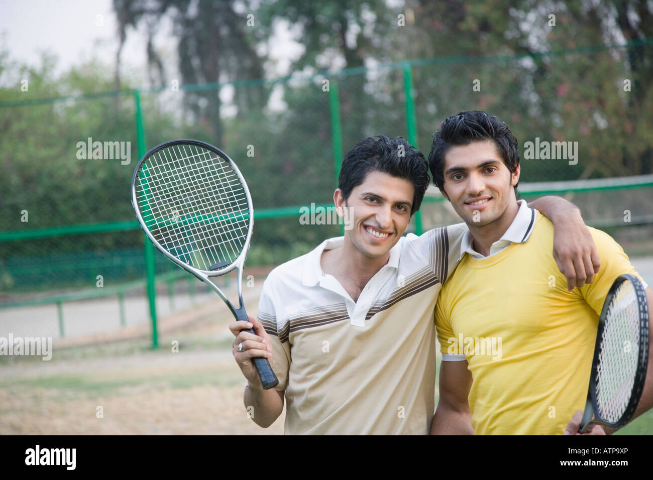Portrait of two young men holding tennis rackets and smiling Stock ...