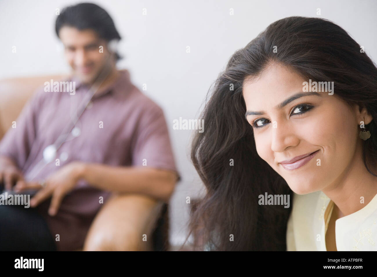 Portrait of a young woman smiling with a young man sitting in the ...