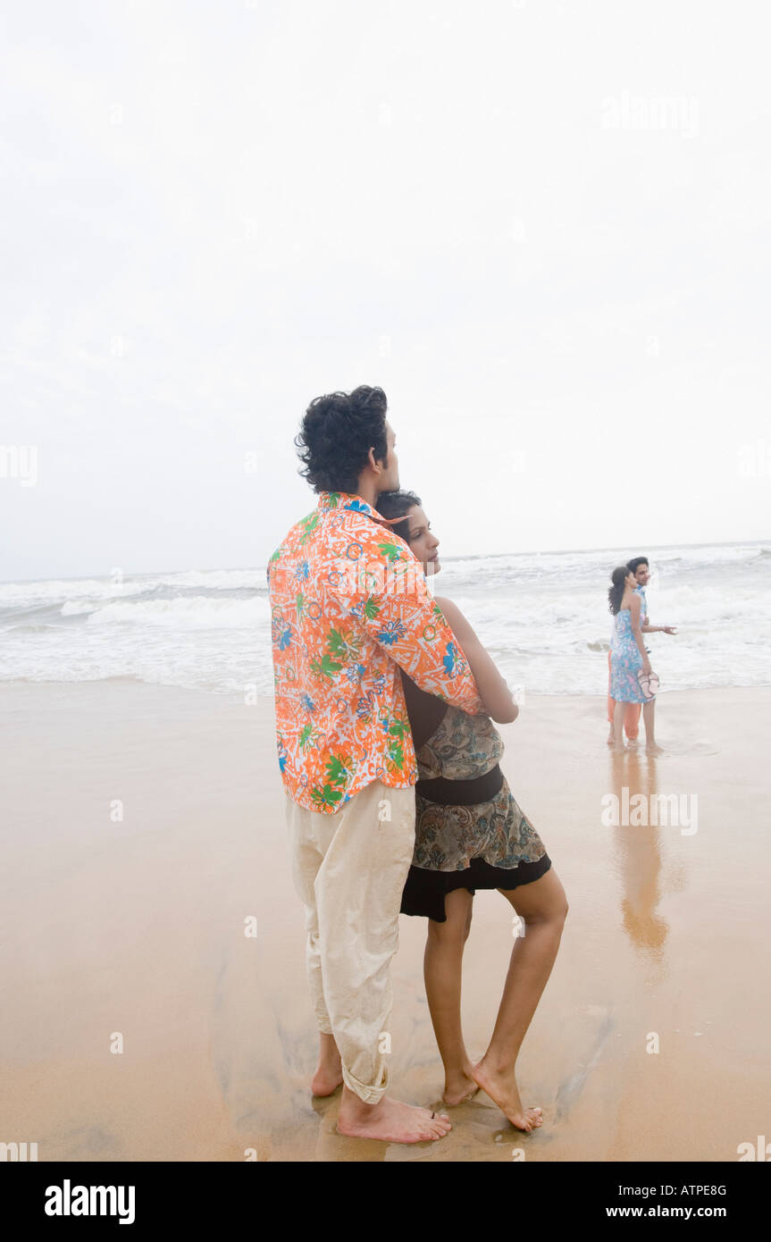 Young man embracing a young woman from behind on the beach Stock Photo ...