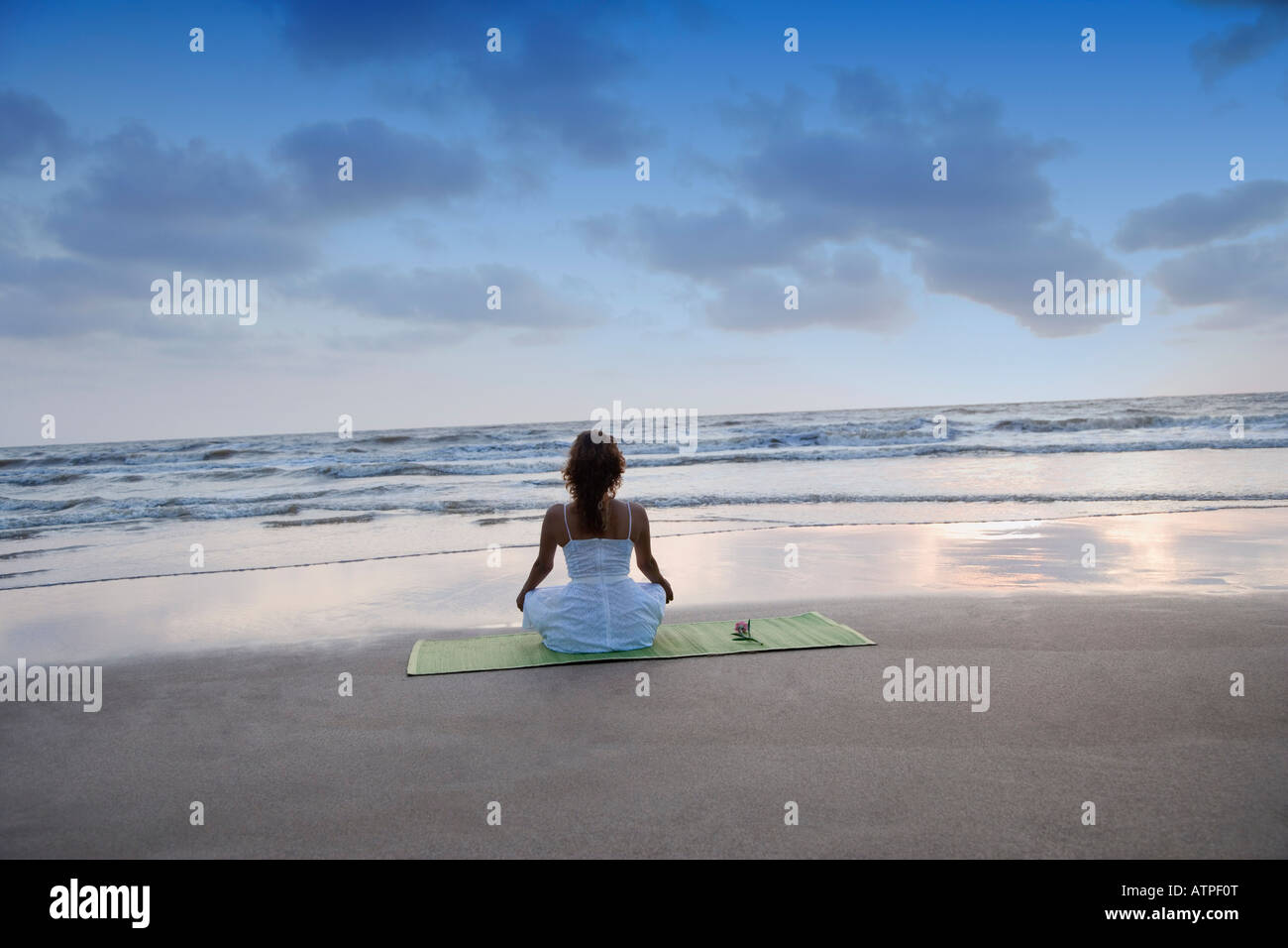 Rear view of a young woman meditating on the beach Stock Photo - Alamy