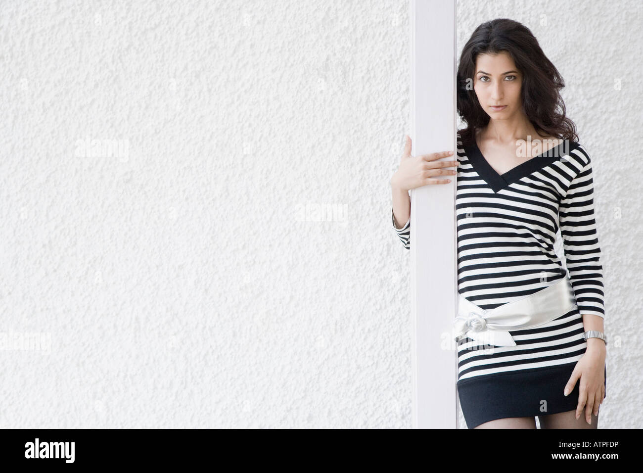 Portrait of a young woman standing in front of a wall Stock Photo - Alamy