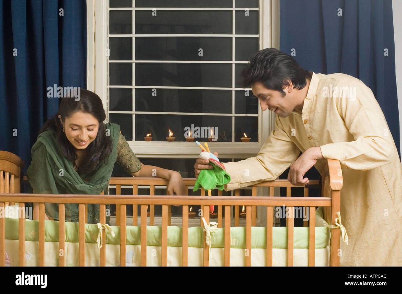 Young Woman And A Mid Adult Man Looking Inside A Crib And Smiling