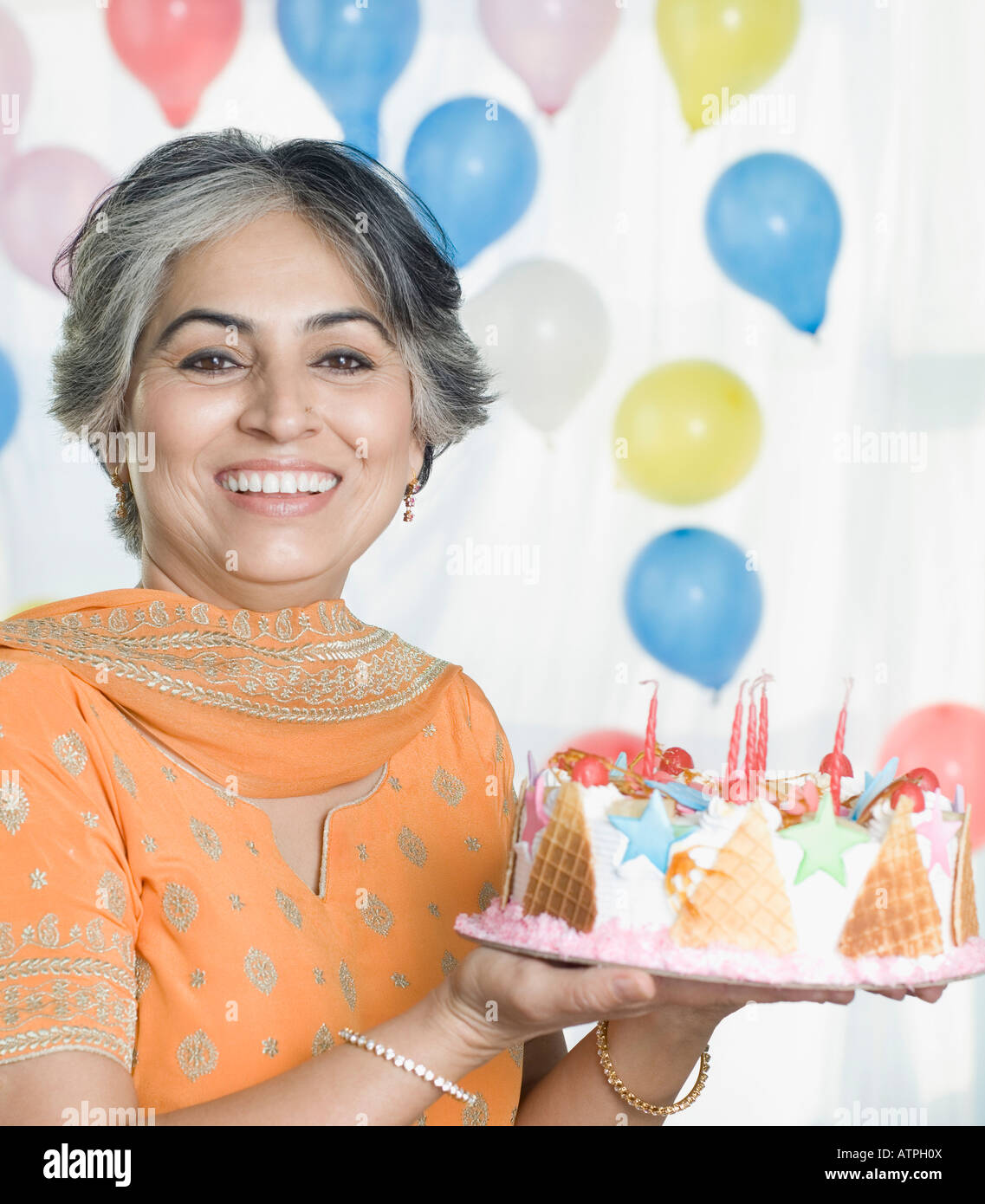 Portrait of a mature woman holding a birthday cake and smiling Stock ...