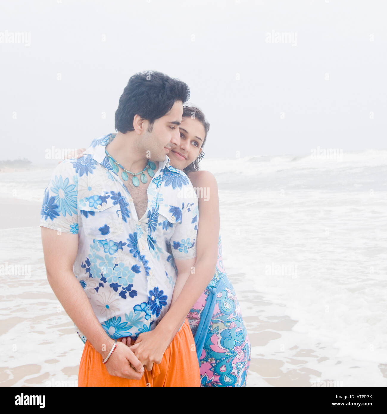 Young woman embracing a young man from behind on the beach Stock Photo ...