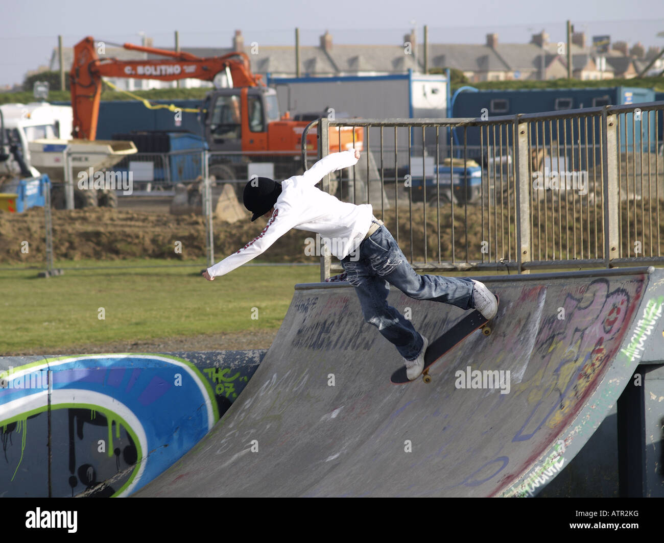 Skateboarder coming down a halfpipe in a skatepark Stock Photo