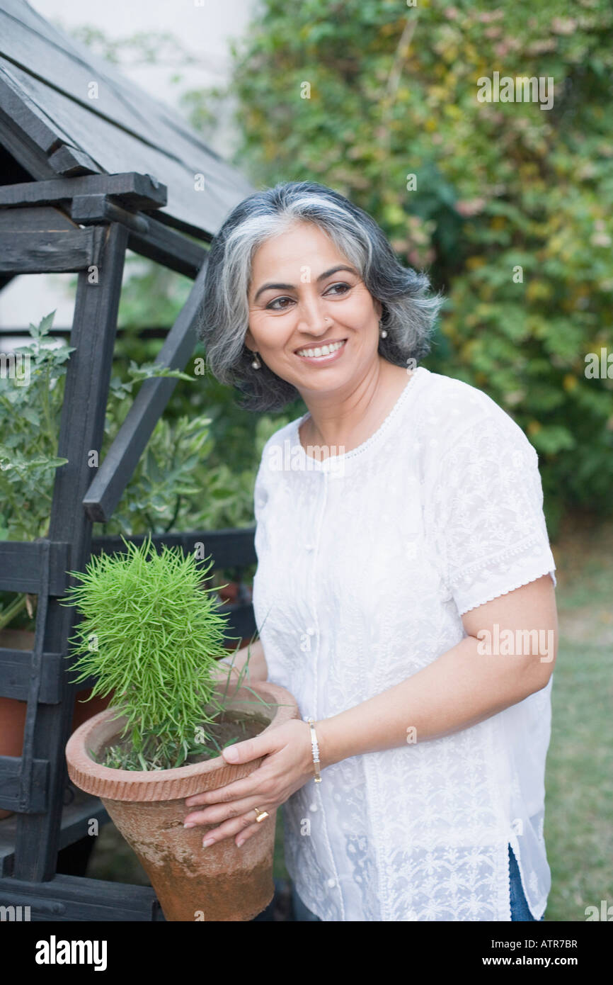 Close-up of a mature woman holding a potted plant Stock Photo - Alamy