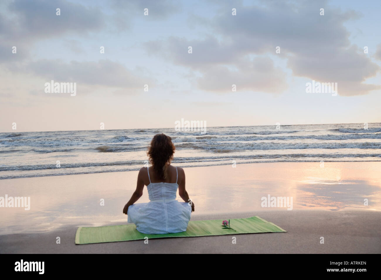 Rear view of a young woman meditating on the beach Stock Photo - Alamy