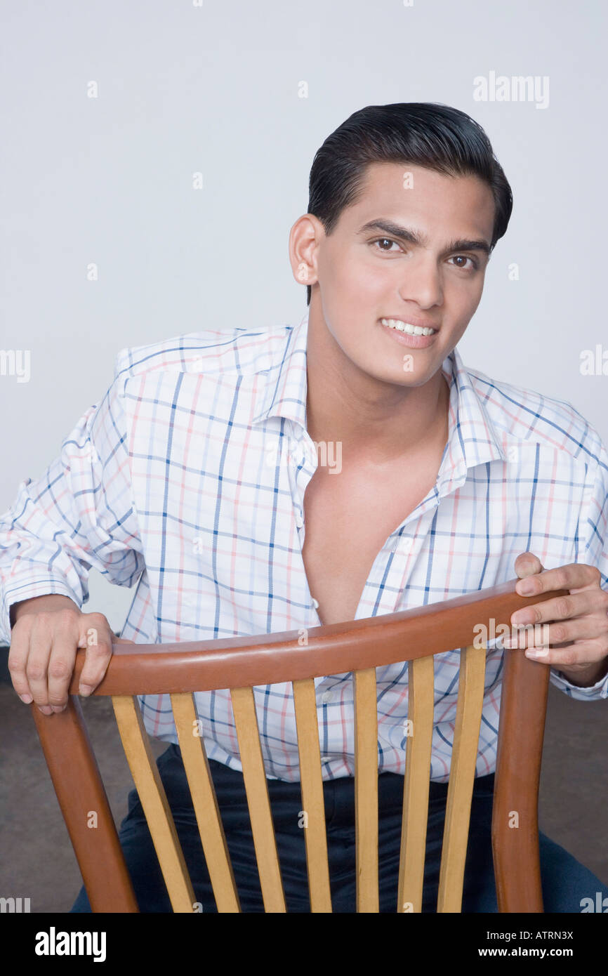 Portrait of a young man sitting on a chair and smiling Stock Photo - Alamy