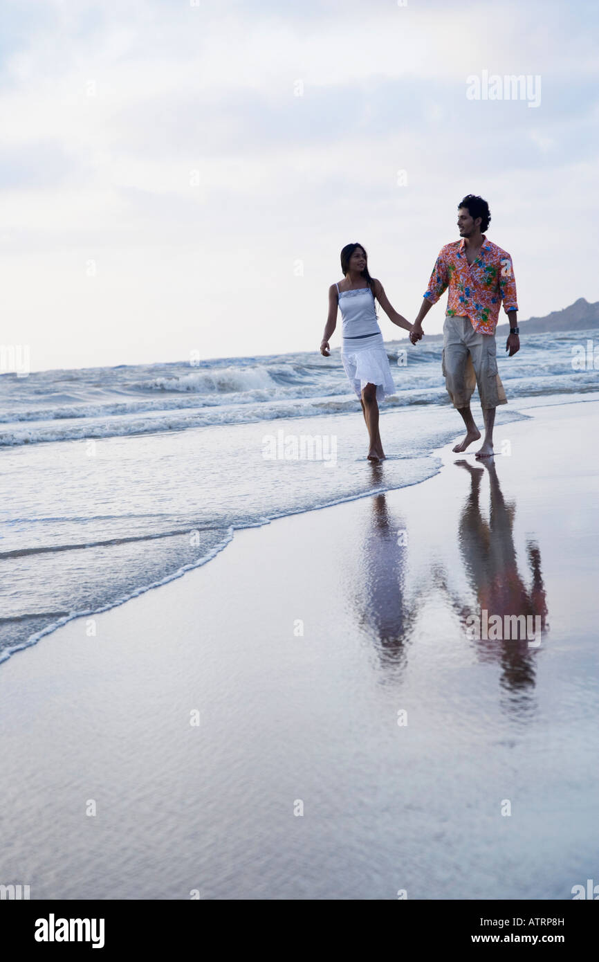 Young couple holding each other's hands and walking on the beach Stock Photo