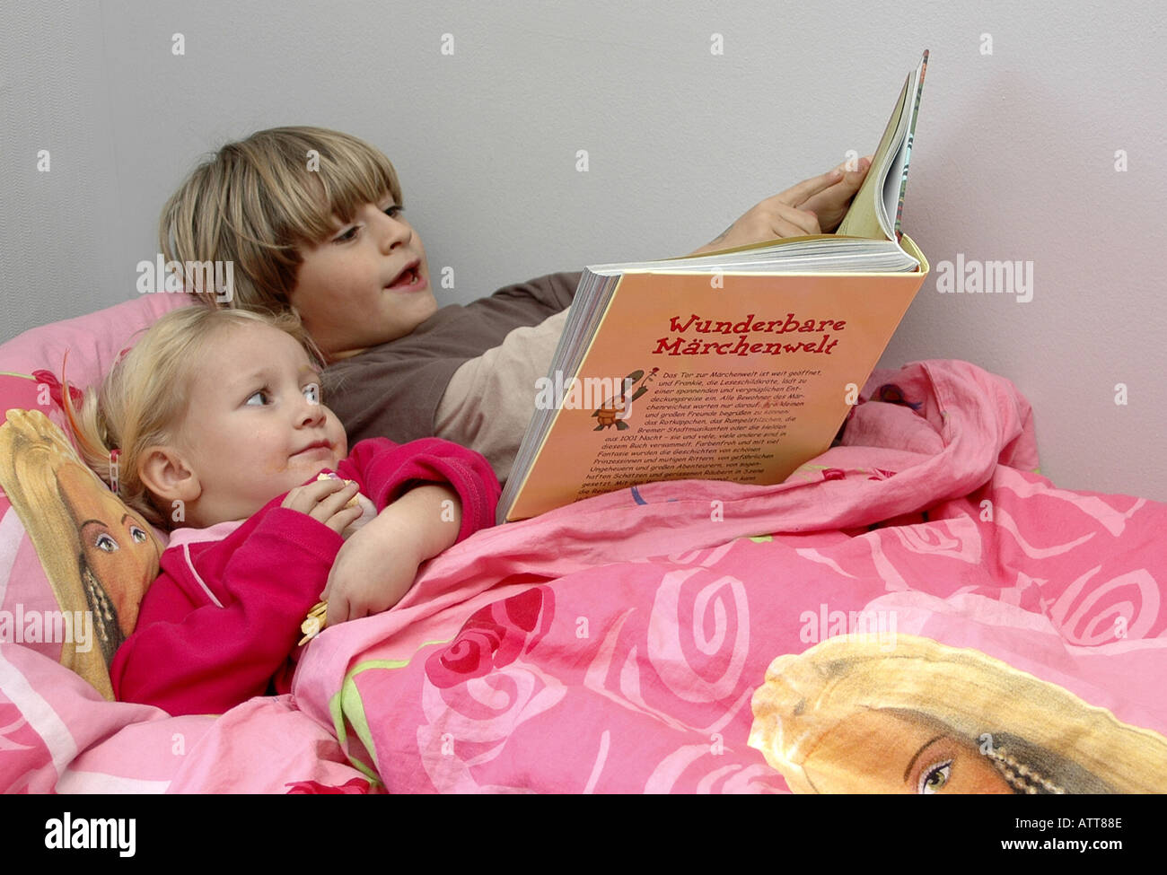 MR Großer Bruder liest kleiner Schwester aus einem Märchenbuch vor MR Two children with book of fairytales in bed Stock Photo