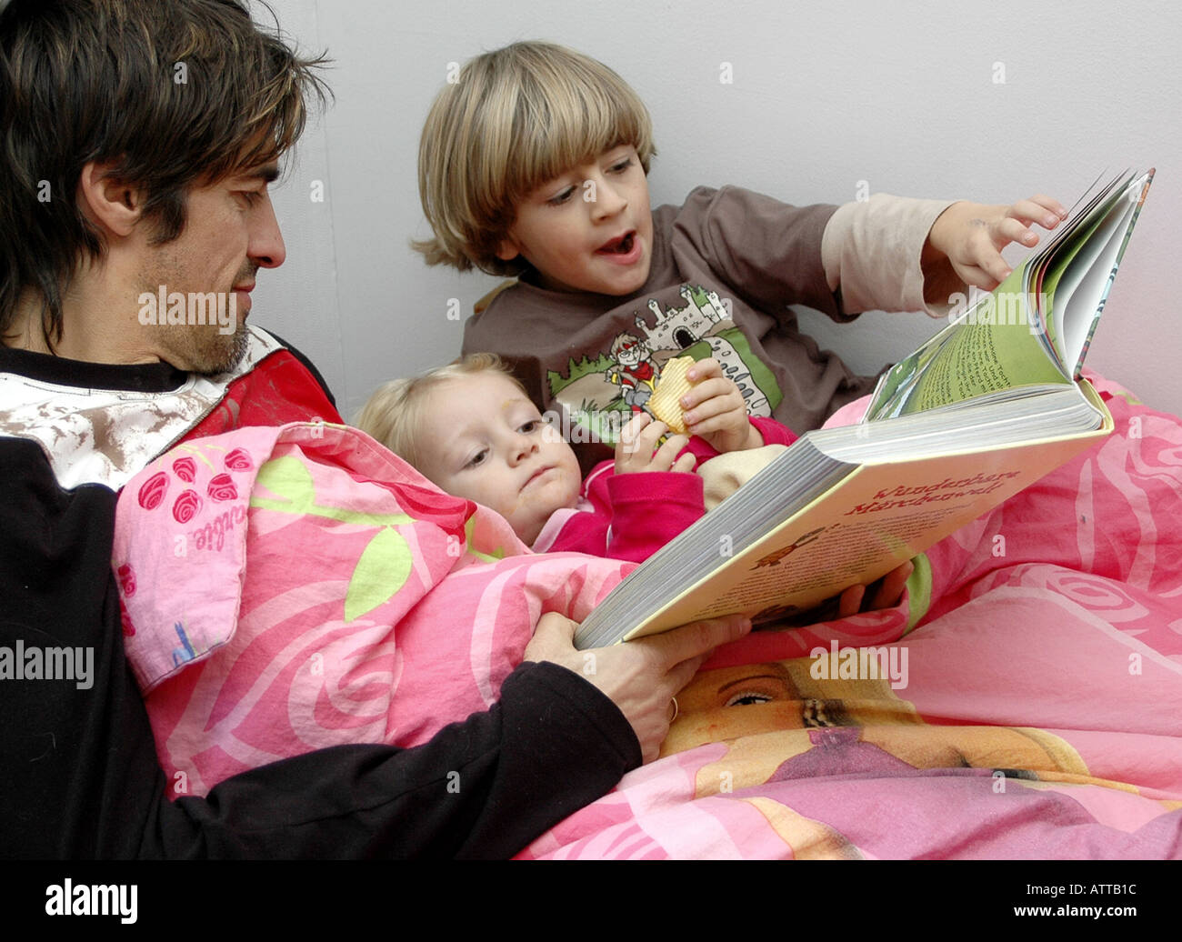 MR Vater liest Kinder aus einem Buch vor MR Father and children with book in bed Bildagentur online Begsteiger Stock Photo