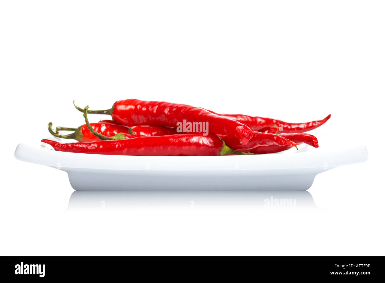 Red hot chili peppers in the dish reflected on white background with shallow DOF Stock Photo