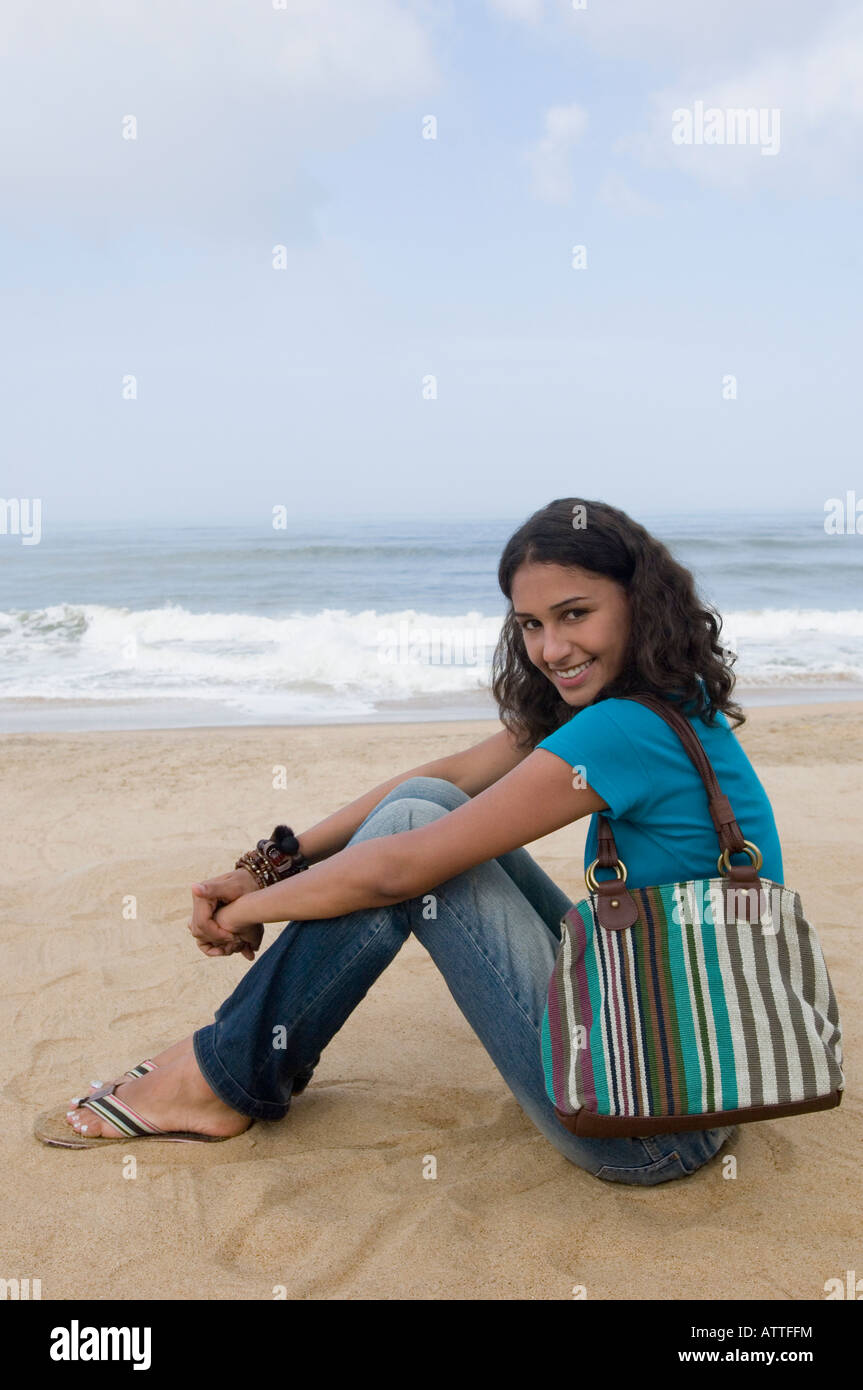 Portrait of a young woman sitting on the beach and smiling Stock Photo ...