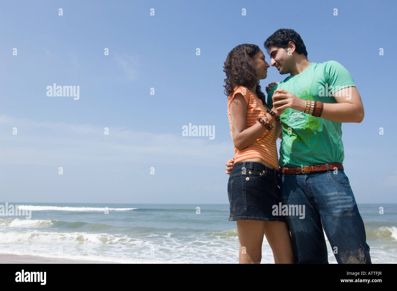 Low angle view of a young man embracing a young woman on the beach ...