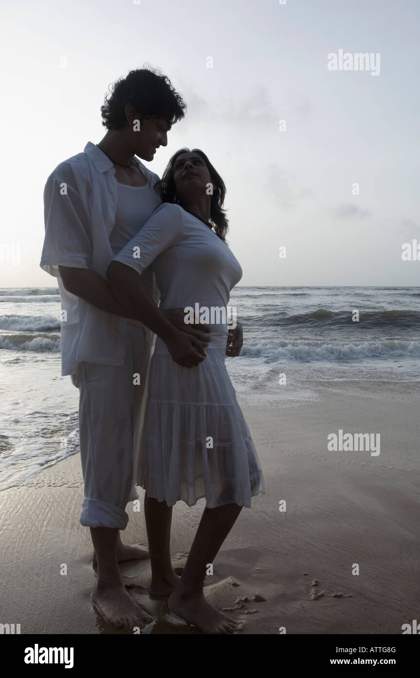 Young man embracing a young woman on the beach Stock Photo - Alamy