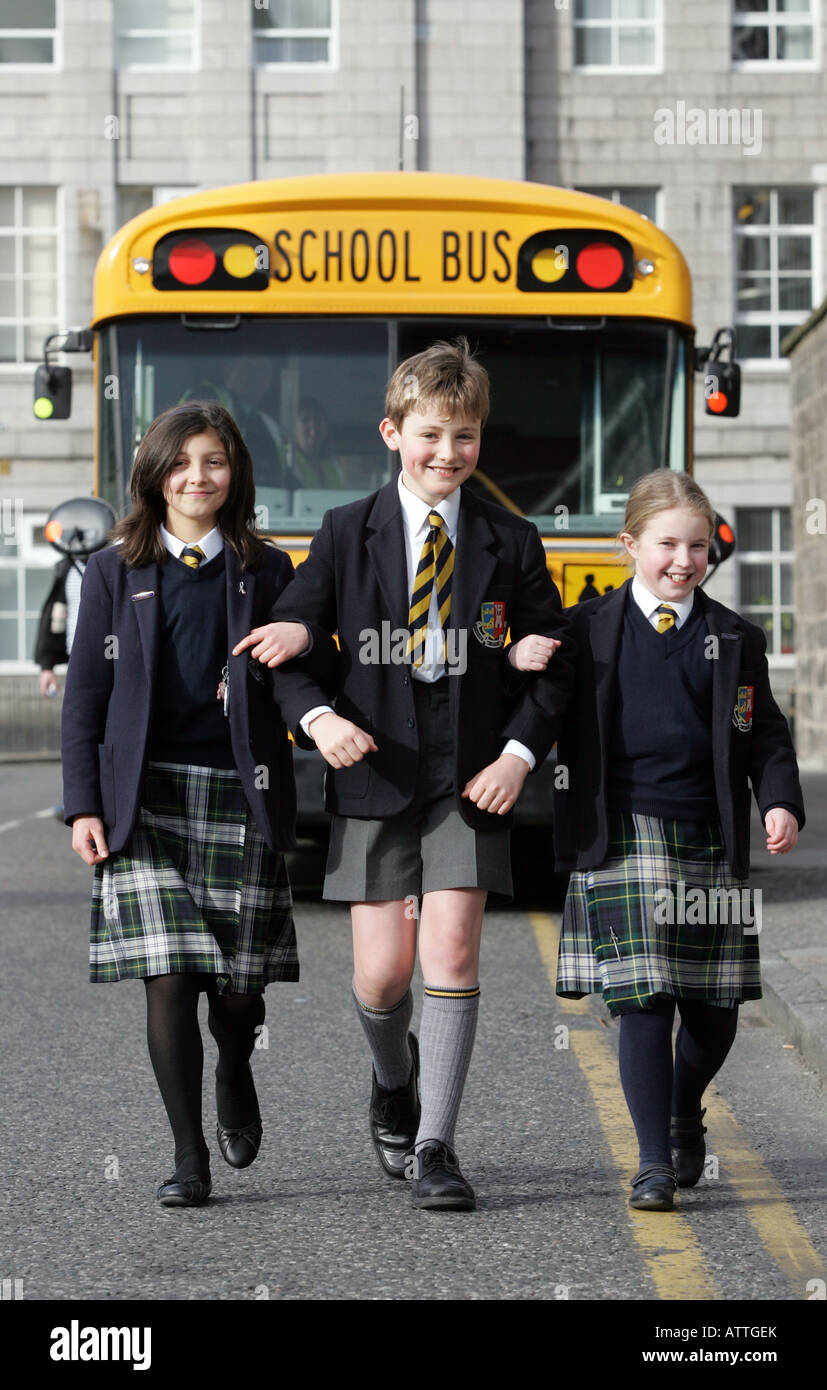Three school children from Robert Gordon's College, Aberdeen, in uniform,  walking away from a yellow school bus Stock Photo - Alamy