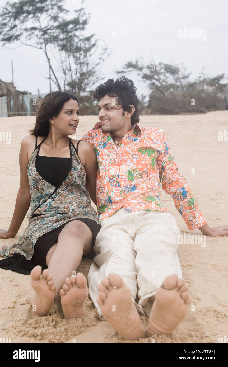 Young couple sitting on the beach and smiling Stock Photo - Alamy