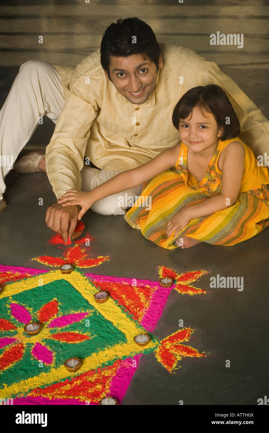 High angle view of a mid adult man making rangoli with his daughter ...