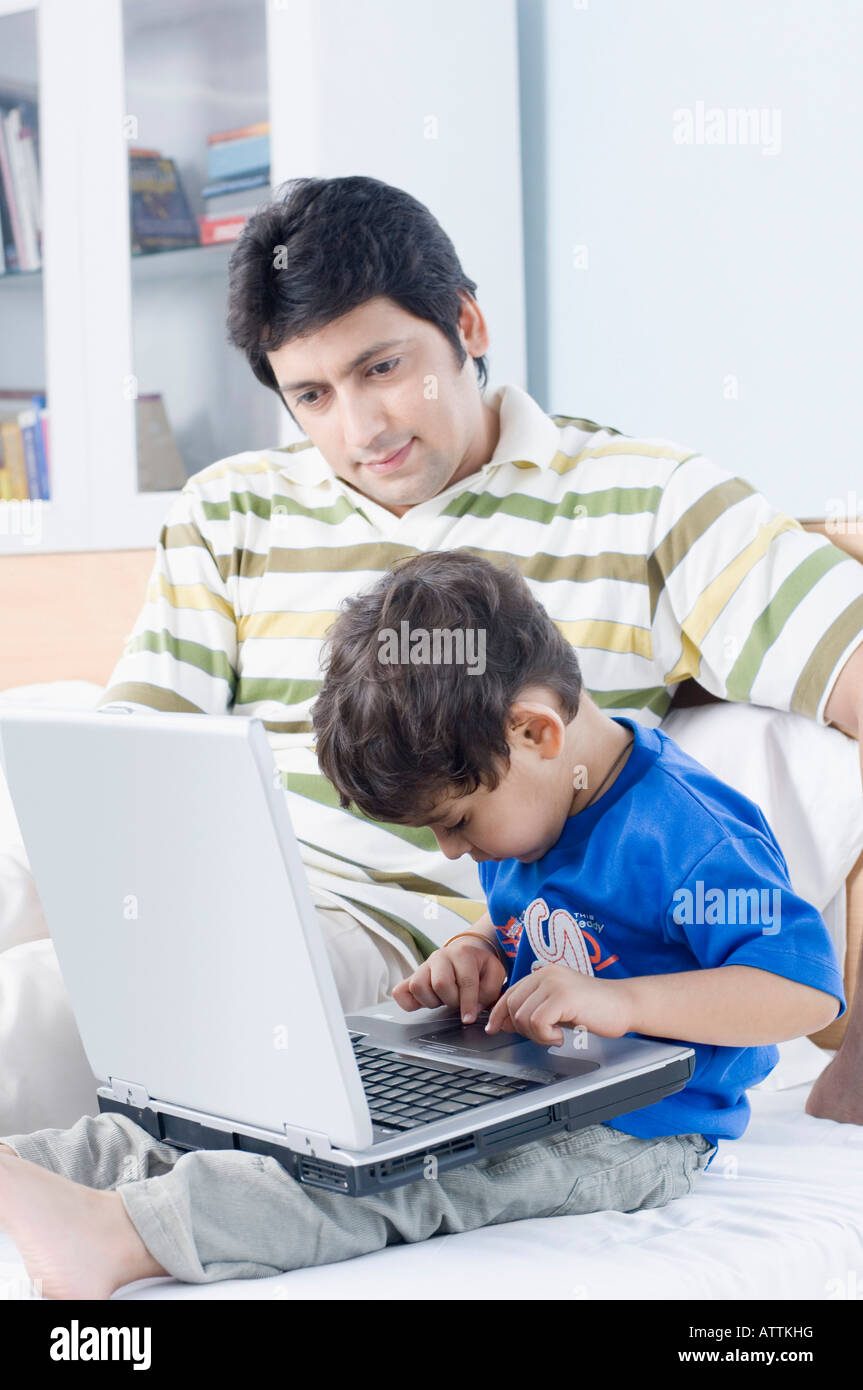 Boy using a laptop with his father sitting beside him Stock Photo - Alamy