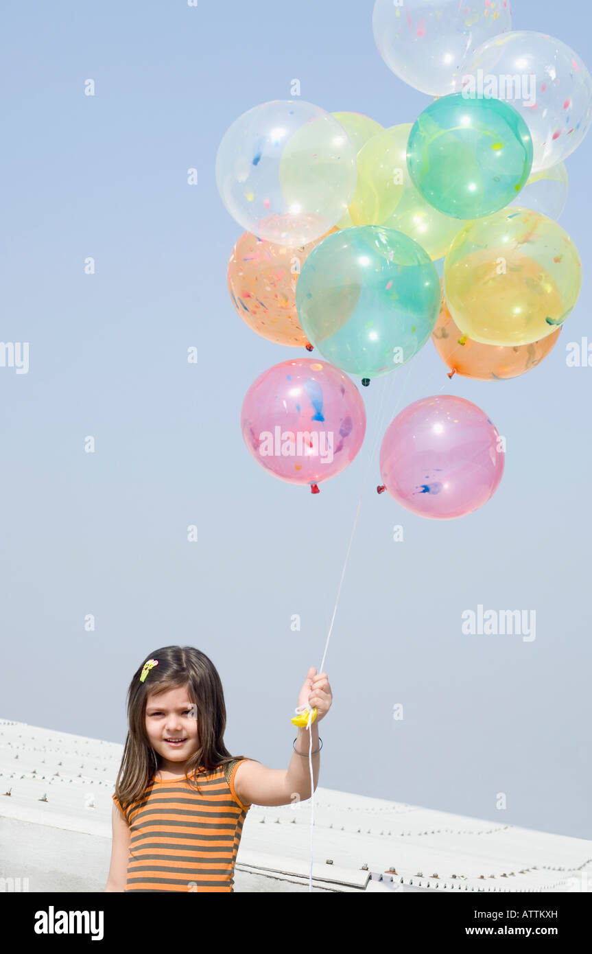 Girl holding balloons and smiling Stock Photo - Alamy
