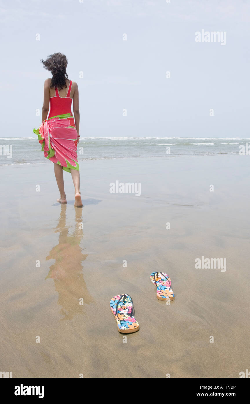 Rear view of a young woman walking on the beach Stock Photo