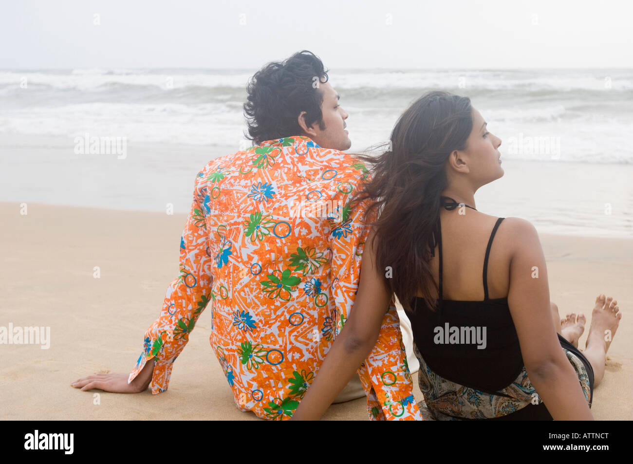 Rear view of a young couple sitting on the beach Stock Photo - Alamy