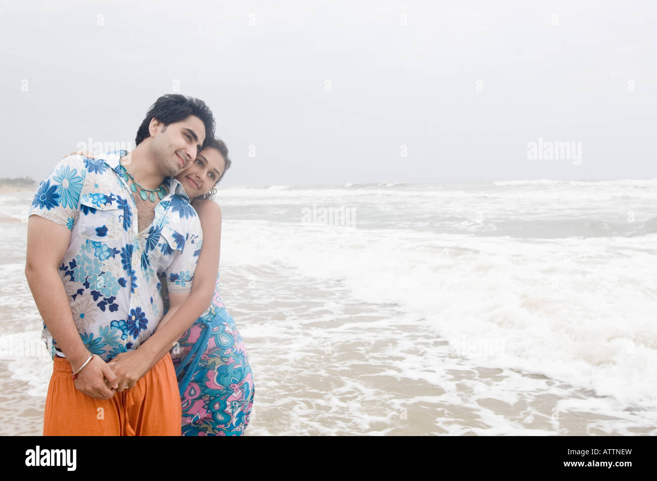 Young woman embracing a young man from behind on the beach Stock Photo ...