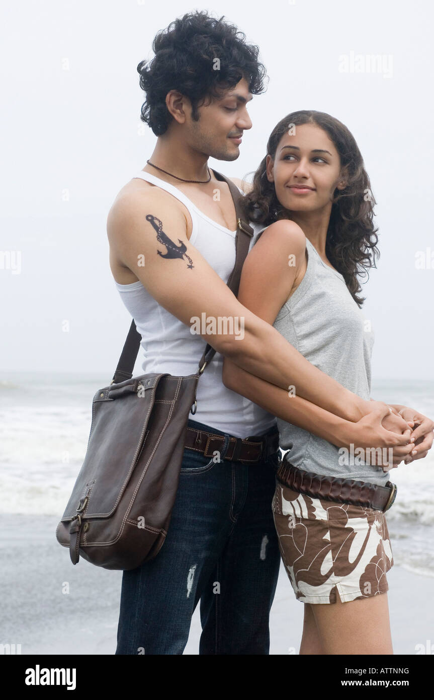 Side profile of a young man embracing a young woman from behind on the ...