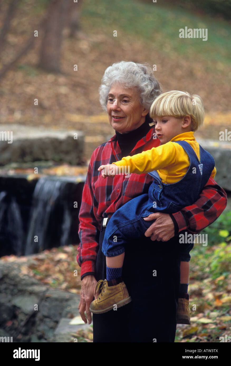 Elderly Woman Holding Her Great Grandson Outdoors in Autumn Stock Photo