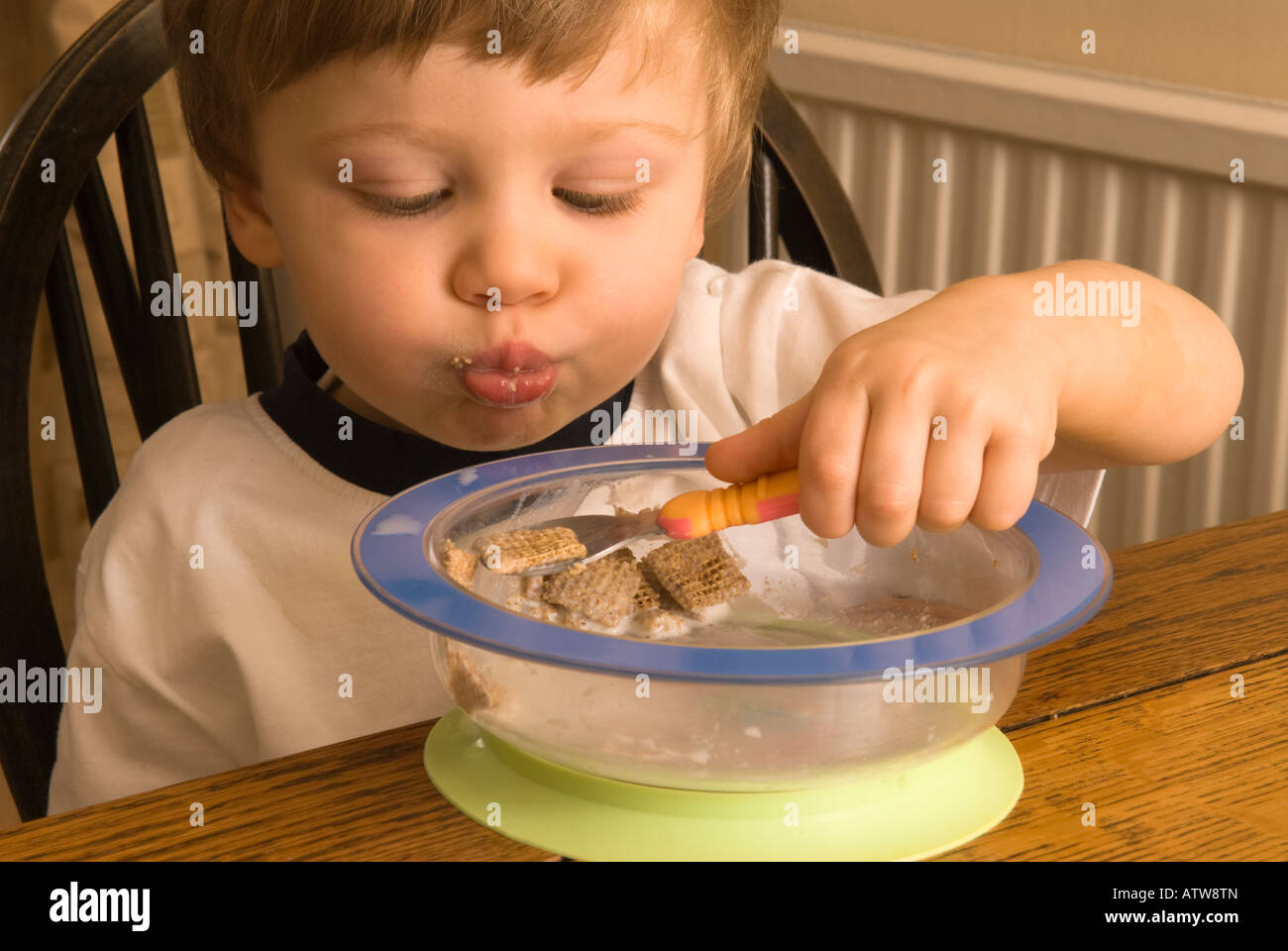 two year old boy eating cereal breakfast learning to use a spoon Stock