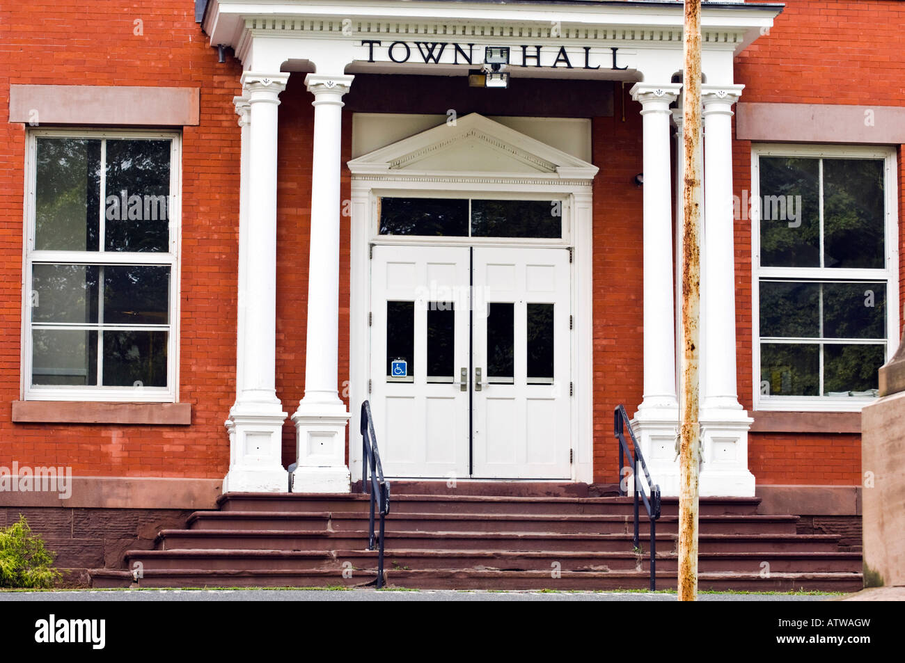 Town hall entrance with white pillars and crumbling steps handicap sign in door window Stock Photo