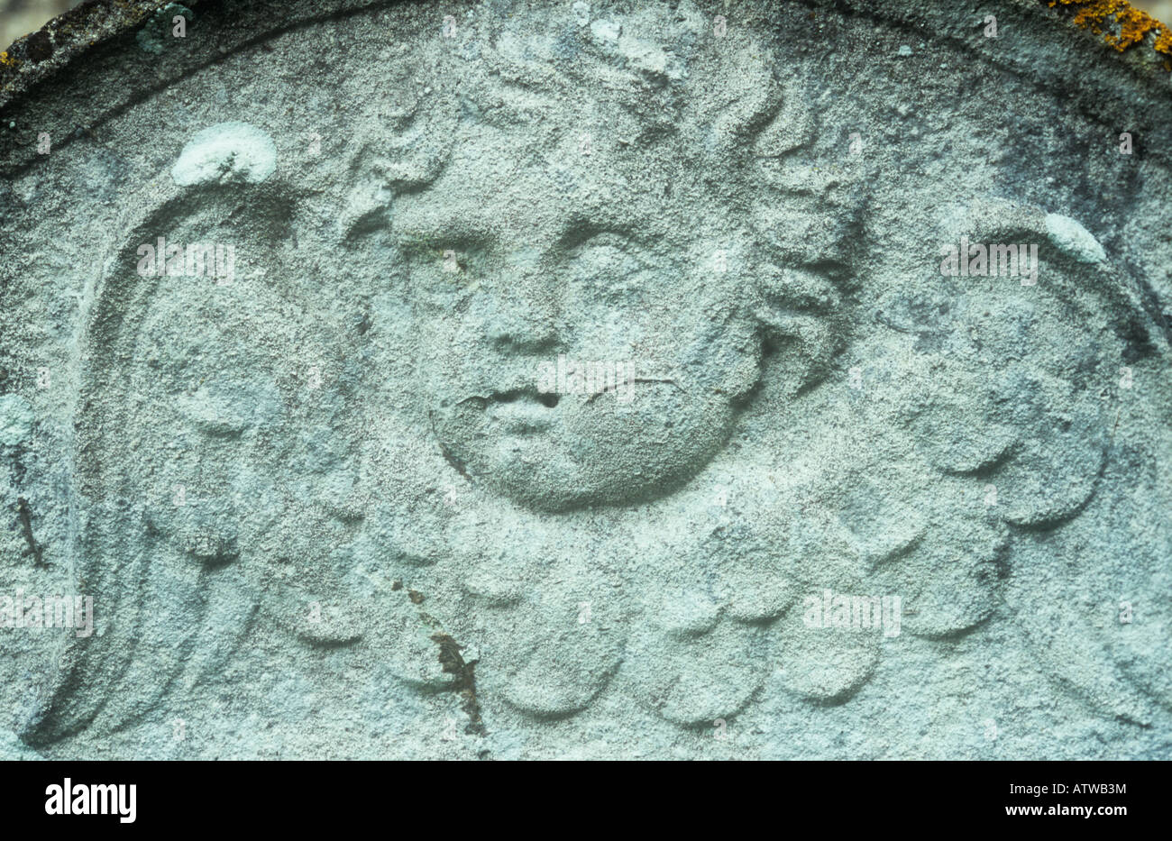 Detail of white-grey gravestone dated 1802 with head of cherubic angel with curly locks of hair and feathery wings Stock Photo