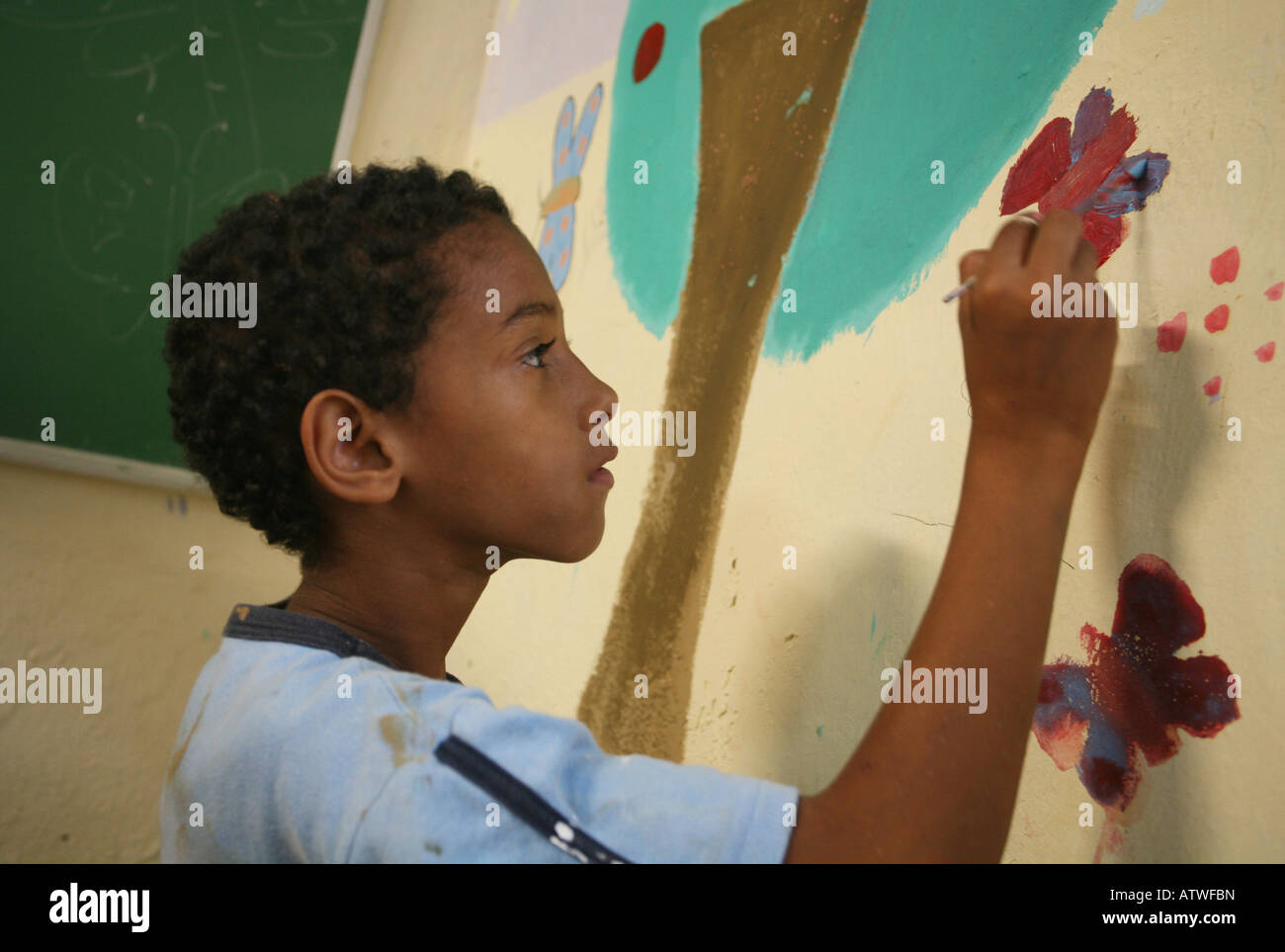 Boy child in favela community centre painting mural as pat of charity aid project, Rio de Janeiro, Brazil, South America Stock Photo