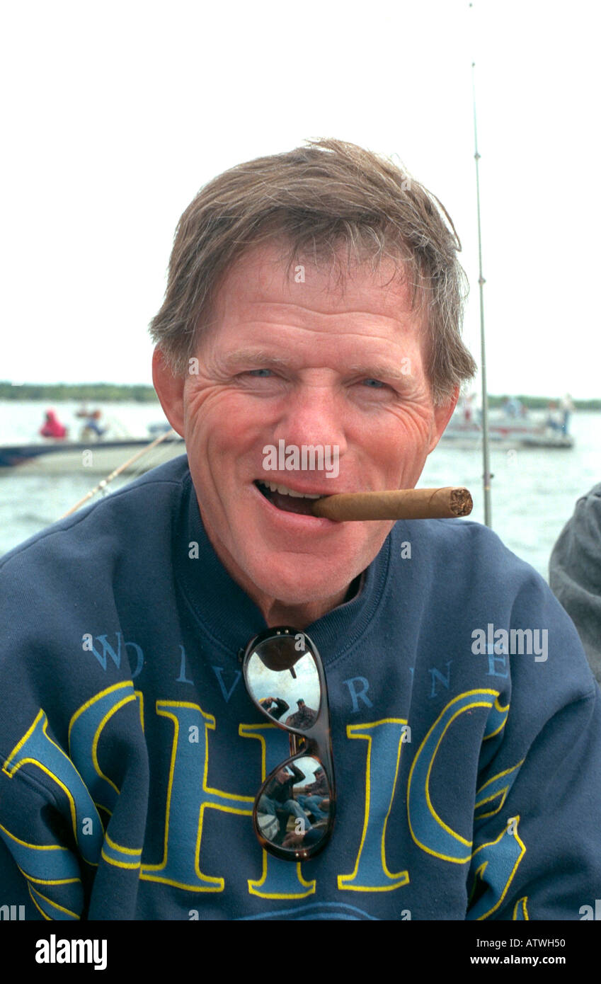 Fisherman age 55 happily smoking cigar on Gull Lake. Nisswa Minnesota USA Stock Photo