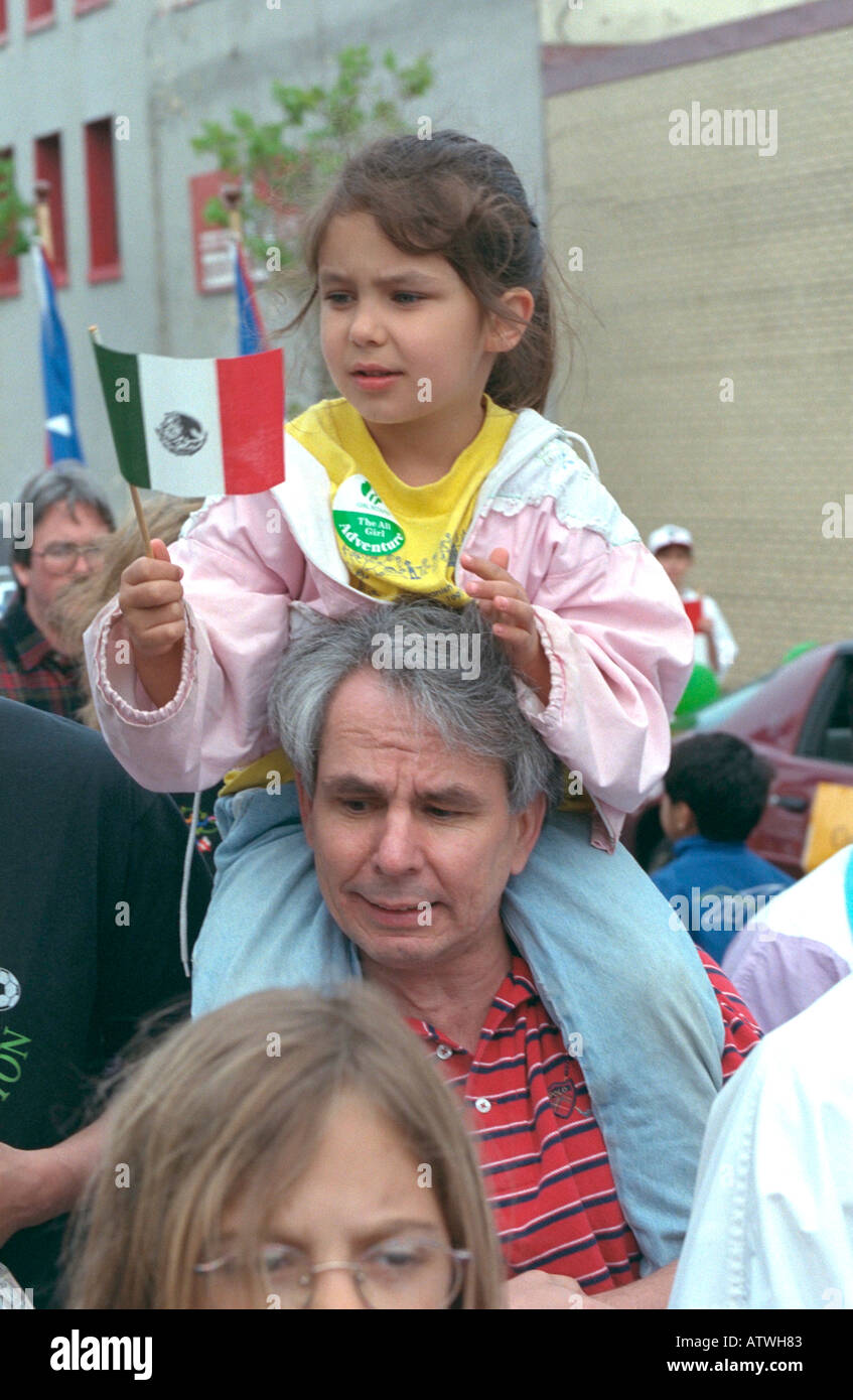 Latino girl riding on fathers shoulders ages 55 and 7 holding Mexican flag. Cinco de Mayo Festival St Paul Minnesota USA Stock Photo