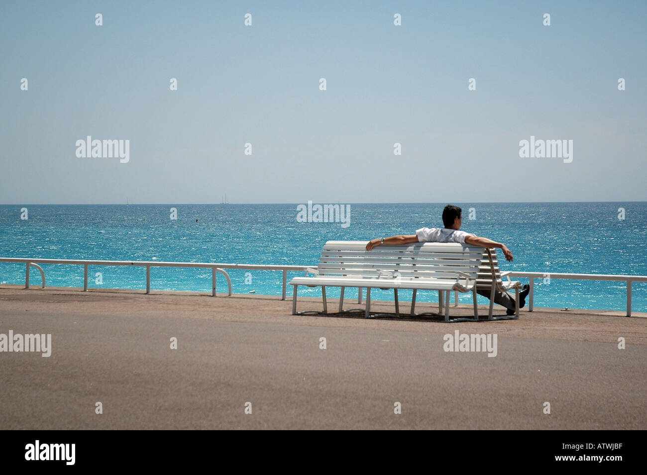 Relaxing and taking in the view on a bench on the seafront in Nice, South of France. Stock Photo