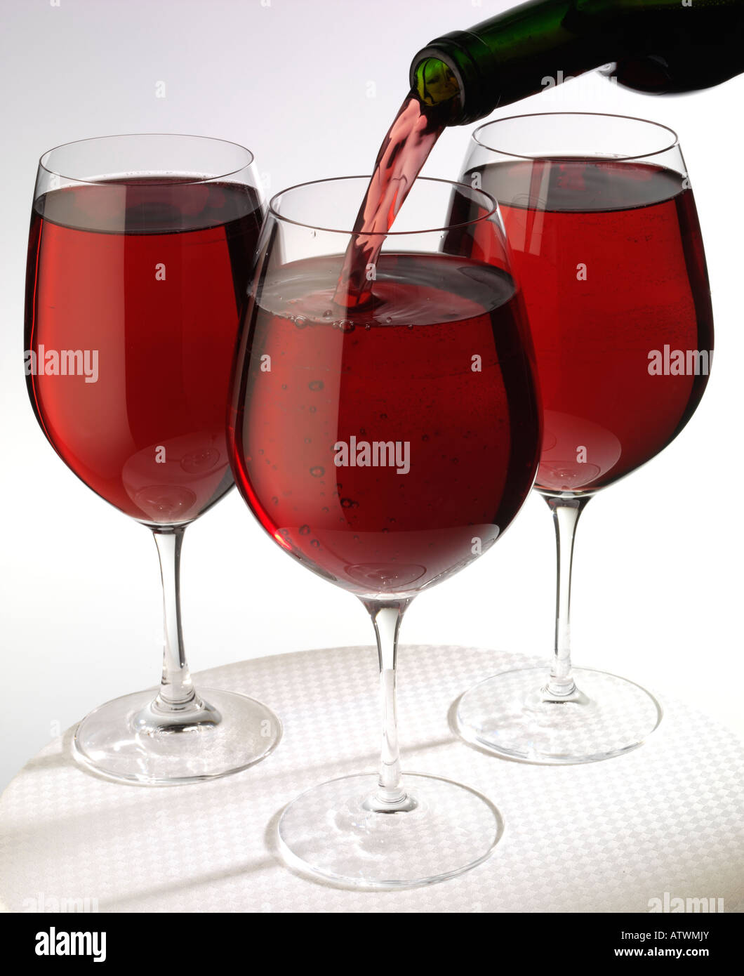 POURING RED WINE INTO THREE GLASSES Stock Photo